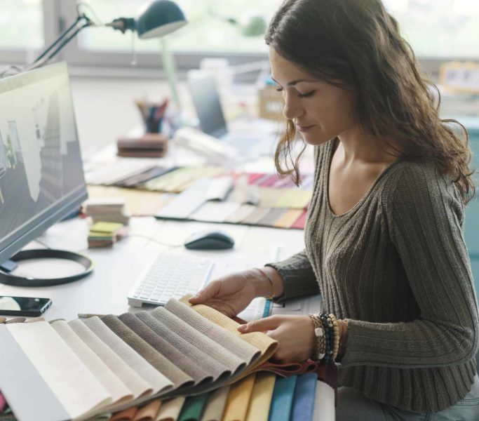 Décoratrice d'intérieur professionnelle travaillant dans son atelier, elle choisit des échantillons de tissus pour son projet